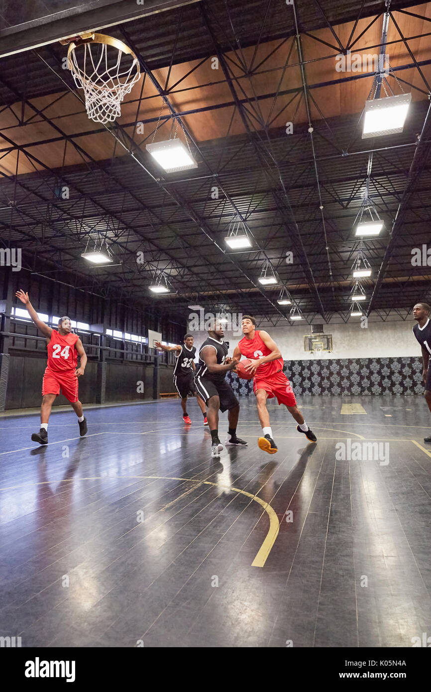 Junge männliche Basketballspieler Basketball spielen auf Gericht im Gymnasium Stockfoto