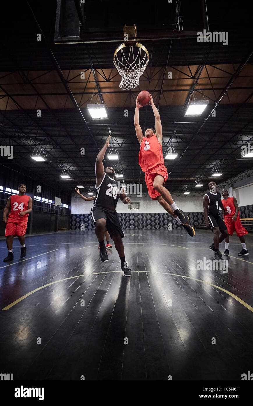 Junge männliche Basketball Player springen dunk Basketball in Spiel auf Gericht im Gymnasium zu Slam Stockfoto