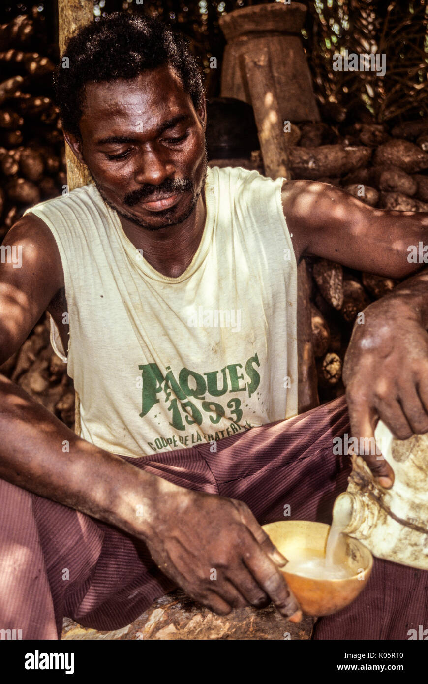 Côte d'Ivoire, Elfenbeinküste, Westafrika. Baole Mann Gießen Palm Wein in eine Schale. Lolobo Dorf, Côte d'Ivoire. Stockfoto