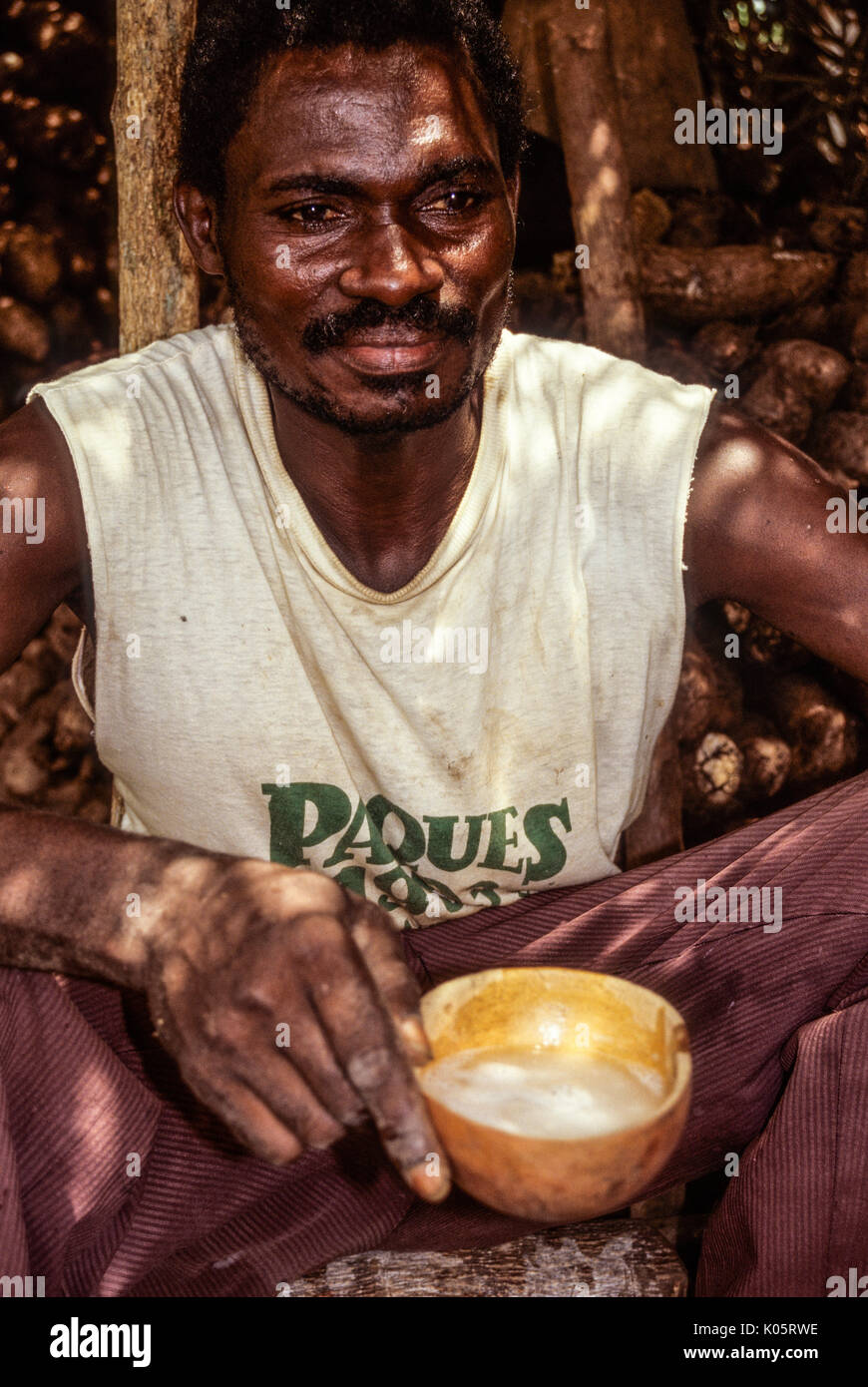 Côte d'Ivoire, Elfenbeinküste, Westafrika. Baole Mann mittleren Alters mit Tasse Palm Wein. Lolobo Dorf, Côte d'Ivoire. Stockfoto