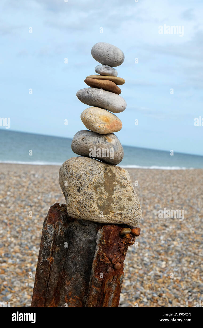 Haufen Steine balancieren auf rostiges Metall post, cley, North Norfolk, England Stockfoto