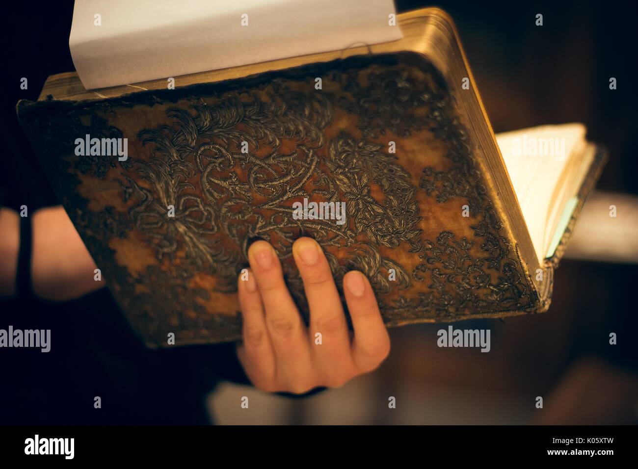 Eine Hand, die offene ein antikes Buch an der Wirbelsäule, 2016. Stockfoto