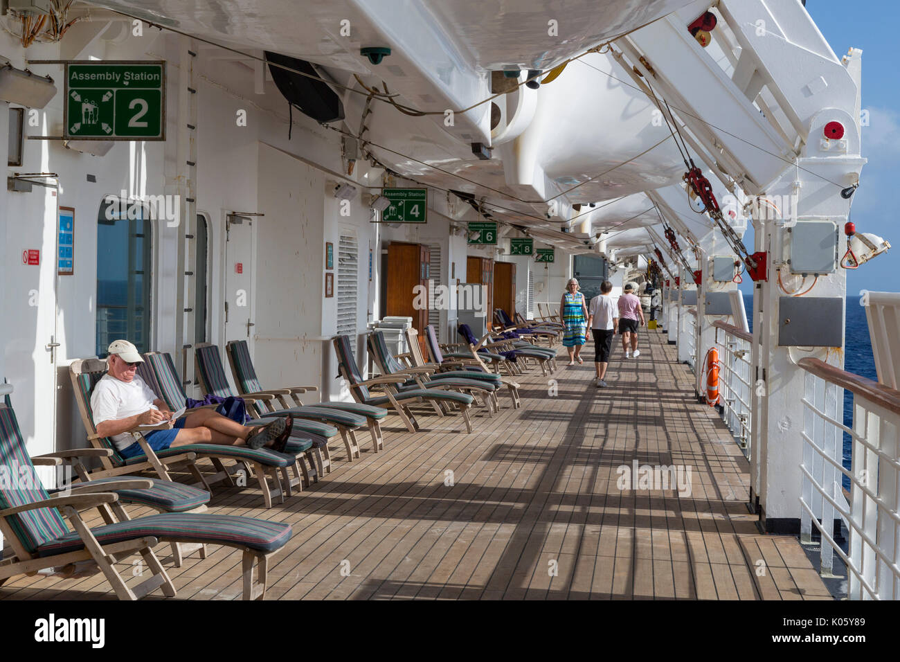 Passagiere der Ausübung oder Lesen auf der Promenade Deck einer Karibik Kreuzfahrt. Stockfoto