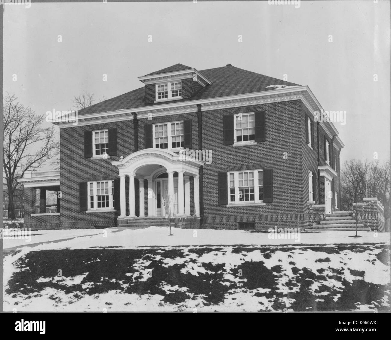 Vorderen Winkel eines zwei-stöckige Haus, das Haus hat eine Veranda, auf der rechten Seite und die Eingangstür mit einem hellen Spalte Struktur eingerichtet wird, alle Fenster sind mit dunklen Fensterläden, Baltimore, Maryland, 1910. Dieses Bild wird von einer Reihe dokumentieren den Bau und den Verkauf von Wohnungen in der Roland Park/Guilford Nachbarschaft von Baltimore, einer Straßenbahn Vorort und eines der ersten geplanten Gemeinschaften in den Vereinigten Staaten. Stockfoto