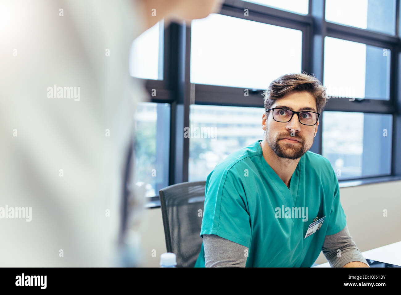 Männliche Krankenschwester in der Begegnung mit Kollegen im Sitzungssaal. Medizinische professionelle Aufmerksamkeit während des Briefings. Stockfoto