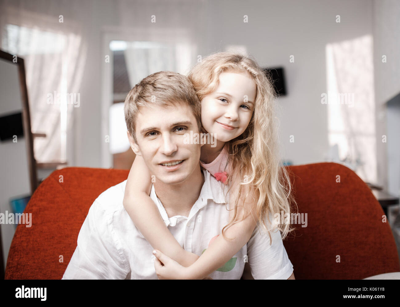 Happy fröhlich Vater und Tochter gemeinsam auf dem roten Sofa zu Hause Stockfoto