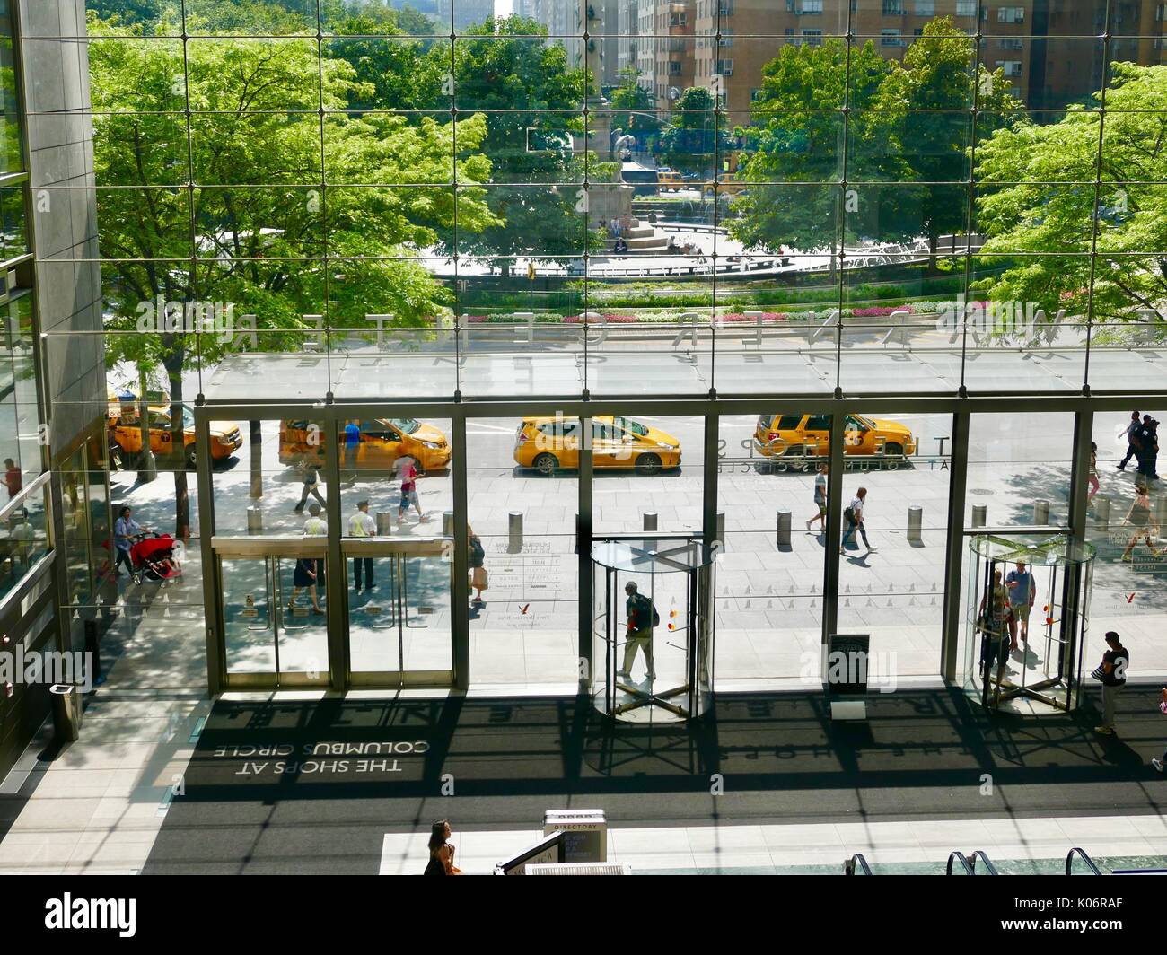 Yellow Cabs ausgerichtet werden, um an den bordstein als durch das Atrium Glas der Geschäfte am Columbus Circle New York, NY, USA gesehen. Stockfoto