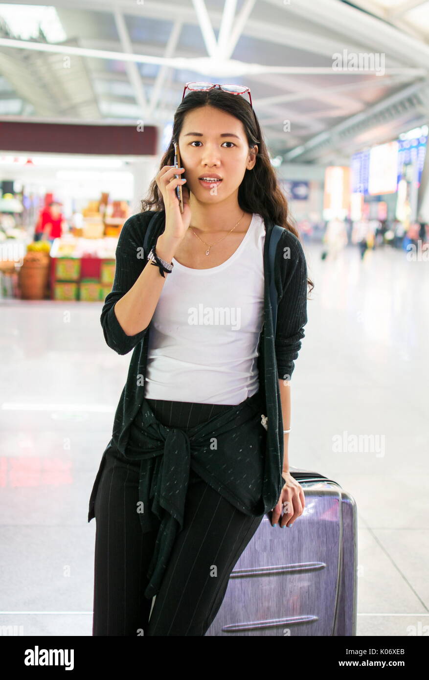 Asiatische Mädchen mit Telefon am Bahnhof Stockfoto