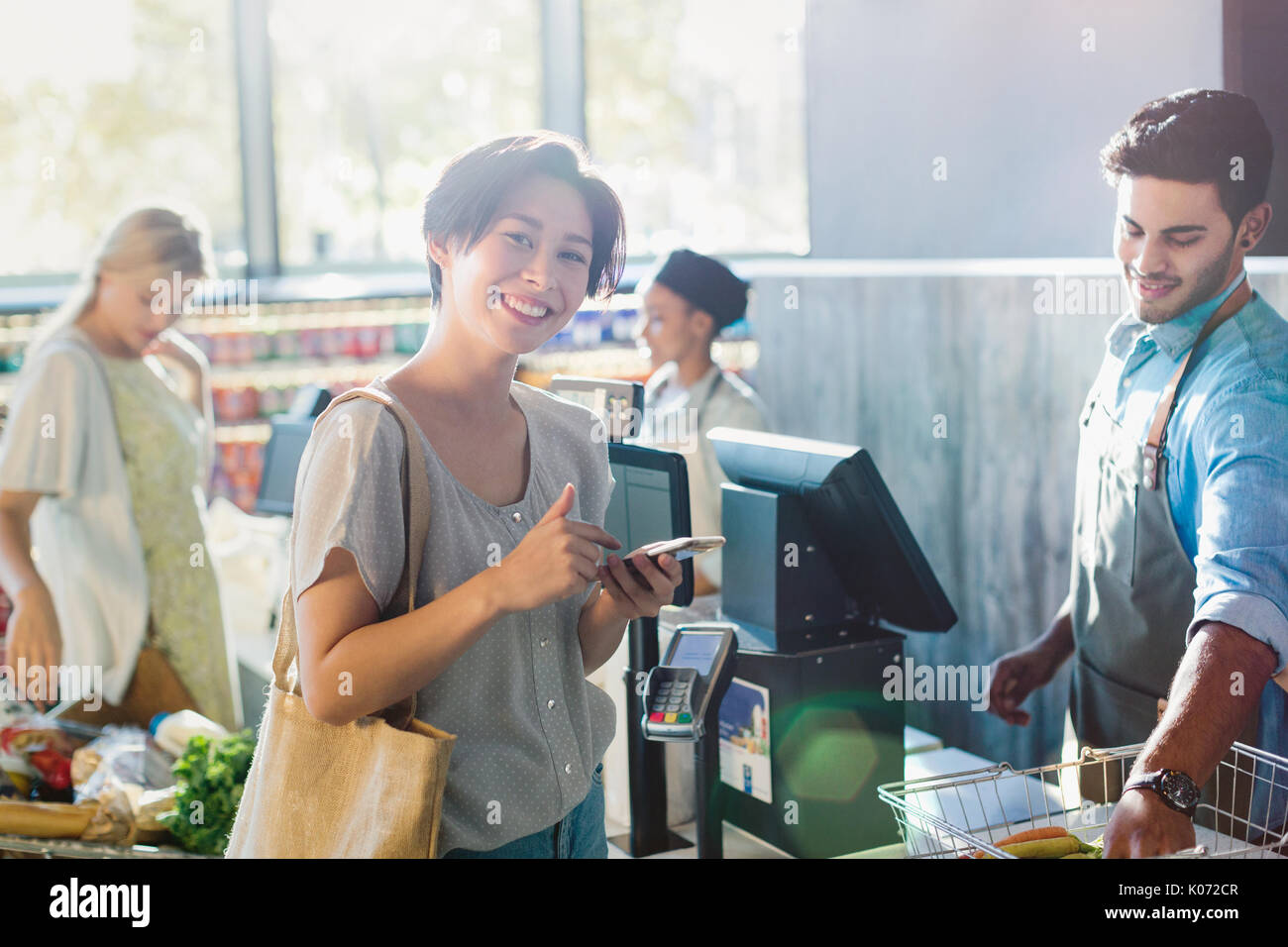 Portrait lächelnden jungen Frau an der Supermarkt Kasse Stockfoto