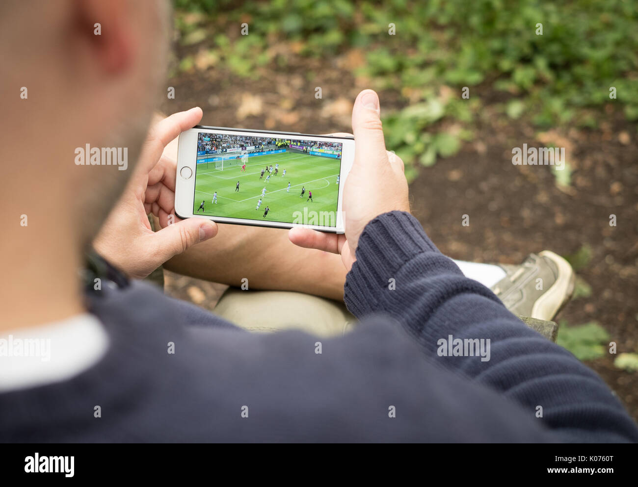 Mann beobachten Streaming Fußballspiel auf dem Smartphone in ländlicher Lage Stockfoto