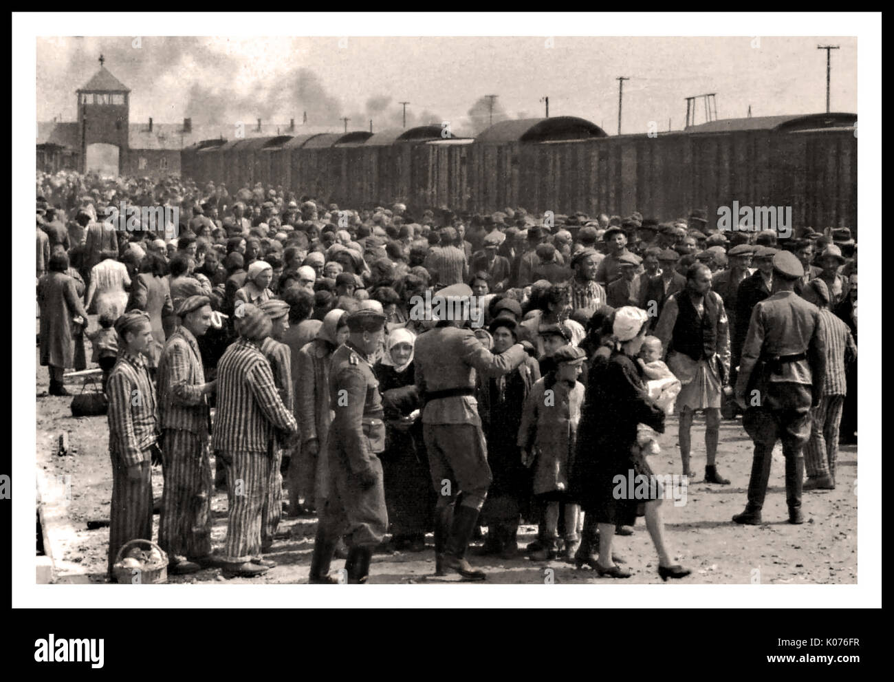 AUSCHWITZ-BIRKENAU ANKUNFT DER HOLOCAUST-GEFANGENEN - Eine starre Vision einer Hölle auf Erden. 1944, Nazis "Grading" (Leben oder peremptory Tod) ahnungslos vor kurzem angekommen Erwachsene und Kinder auf Eisenbahnstrecke, vor dem Eingang zum Vernichtungslager Auschwitz-Birkenau. Das berüchtigte Auschwitz-Lager wurde auf Befehl Adolf Hitlers in den 1940er Jahren während der Besetzung Polens durch Nazi-Deutschland während des Weltkrieges 2 gegründet, weiter ermöglicht durch Heinrich Luitpold Himmler, den Reichsführer des Schutzstaffels, und führendes Mitglied der Nazi-Partei Deutschlands Stockfoto
