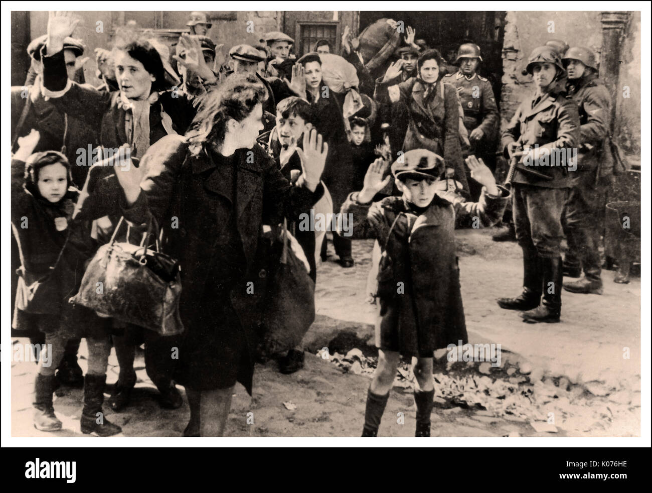 WARSCHAUER GHETTOJUNGE ÜBERGABE JÜDISCHE FRAUEN und KINDER Dieses ergreifende Bild aus dem Jahr WW2 zeigt jüdische Männer Frauen und Kinder aus dem Warschauer Ghetto, die sich nach dem mutigen, tapferen Aufstand deutschen Soldaten ergeben. Evakuierung des Warschauer Ghettos, die während der Nürnberger Gerichtsverfahren als Beweismittel verwendet wurde ( Stroop-Bericht), 1945/6. Beachten Sie den kleinen polnischen Jungen im mittleren Hintergrund mit bewundernswertem Widerstand gegen den nationalsozialistischen deutschen Fotografen, der seine Zunge vor die Kamera streute Stockfoto
