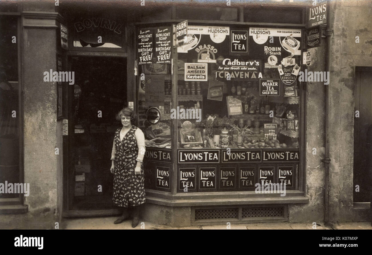 Eine Frau, die vor dem Laden eines Lebensmittelhändlers steht Stockfoto