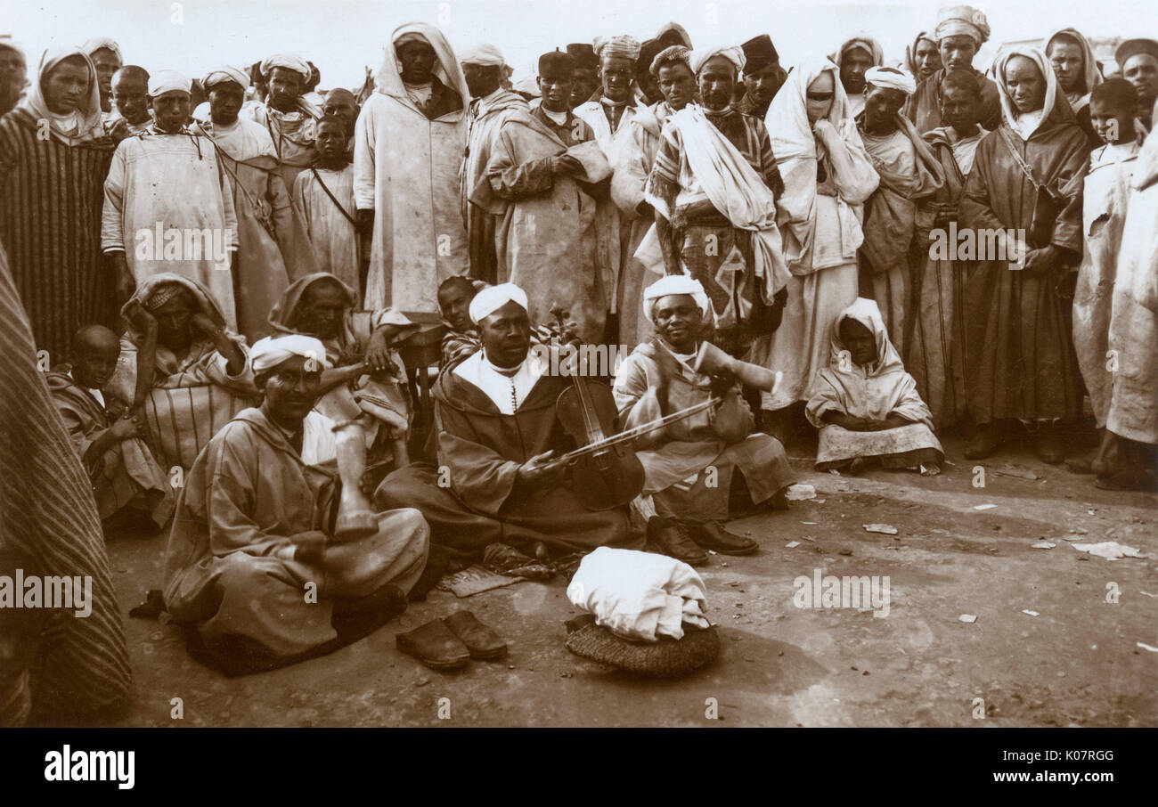 Chleuh (Shilha, Shluh) Musiker, eine Untergruppe der Berber in Marokko. Ein Mann spielt eine Violine, während zwei andere Schlaginstrumente. Datum: ca. 1930 Stockfoto