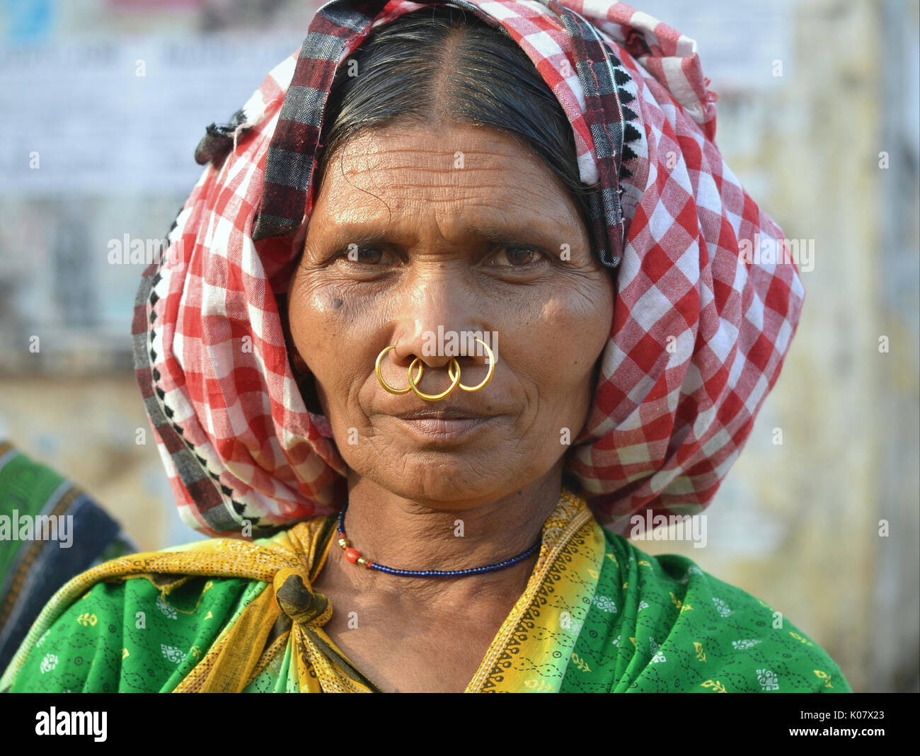 Ältere indische Adivasi-Frau mit drei goldenen Nasenringen posiert für die Kamera. Stockfoto