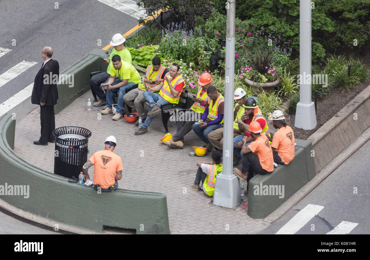 Eine Gruppe von Bauarbeitern essen Mittagessen mit einem Mann in einem Geschäft in der Nähe, NYC Stockfoto