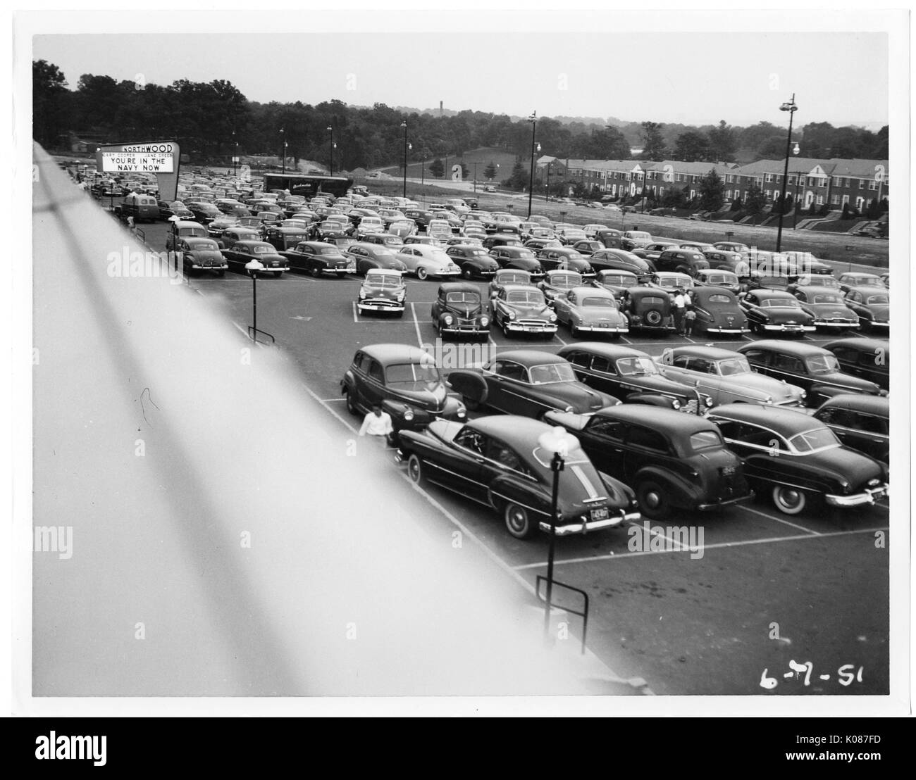 Parkplatz von Northwood Einkaufszentrum mit Hunderten von Autos, Zeichen im Hintergrund, die lautet: "Sie in der Marine sind Jetzt', Bäume, Häuser und Straßenbeleuchtung im Hintergrund, Baltimore, Maryland, 1951. Stockfoto