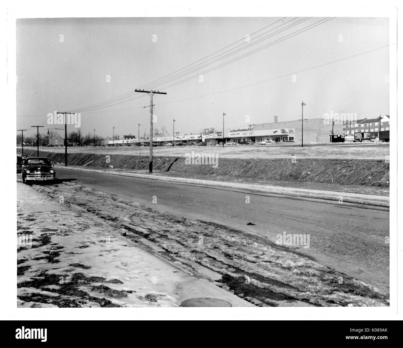 Foto, kommerzielle Gebäude der Northwood Einkaufszentrum (über die Straße) und Autos auf der Seite der Straße geparkt, mit Wohnbauten und Bäume im Hintergrund, Baltimore, Maryland, 1951. Stockfoto