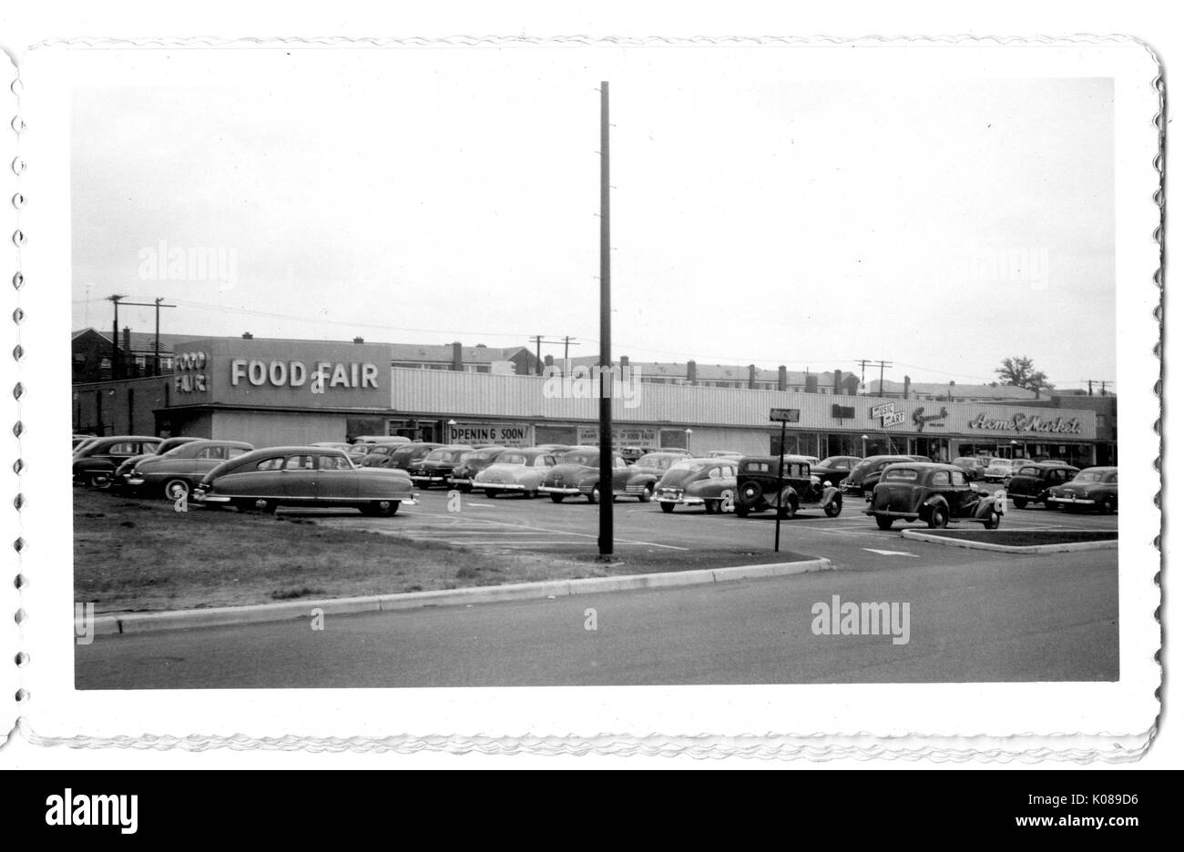 Foto der Parkplatz für die Northwood Einkaufszentrum, mit Autos und gewerblichen Bauten, wie zum Beispiel Essen Messe mit einem 'Öffnen bald!" Schild im Fenster, Baltimore, Maryland, 1951. Stockfoto
