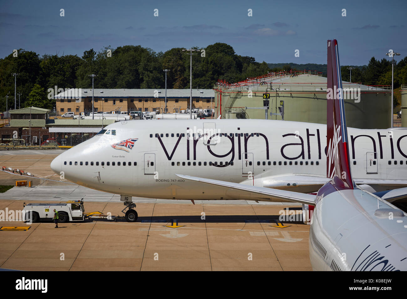 Pushback Traktoren und Schlepper bewegt sich Virgin Atlantics Lackierung 474 400 Tinker Belle am Nordterminal des Flughafen Gatwick Stockfoto