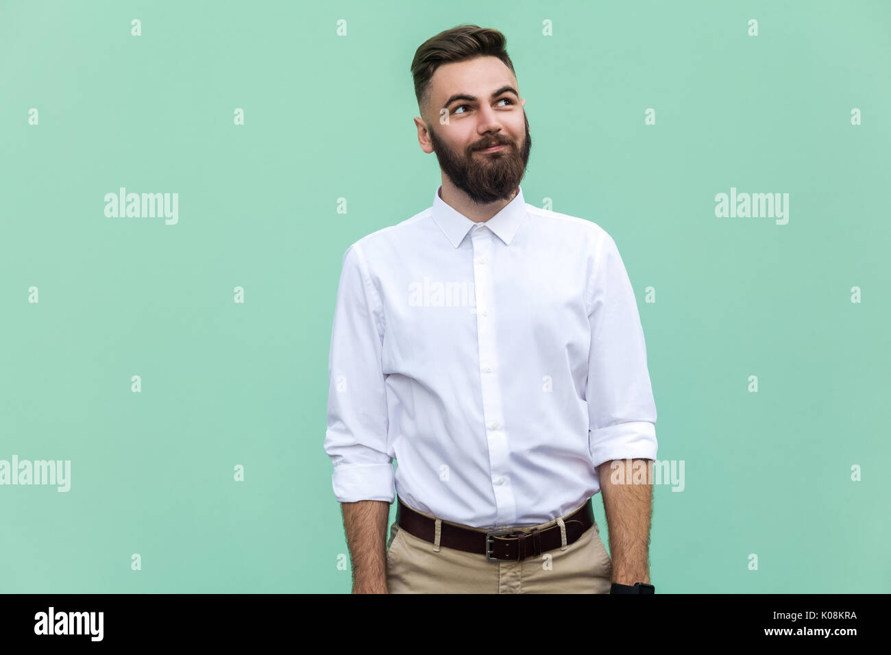 Fliegen der Gedanken. Nachdenklich bärtigen Geschäftsmann weg schauen, während gegen die hellgrüne Wand. Studio shot Stockfoto