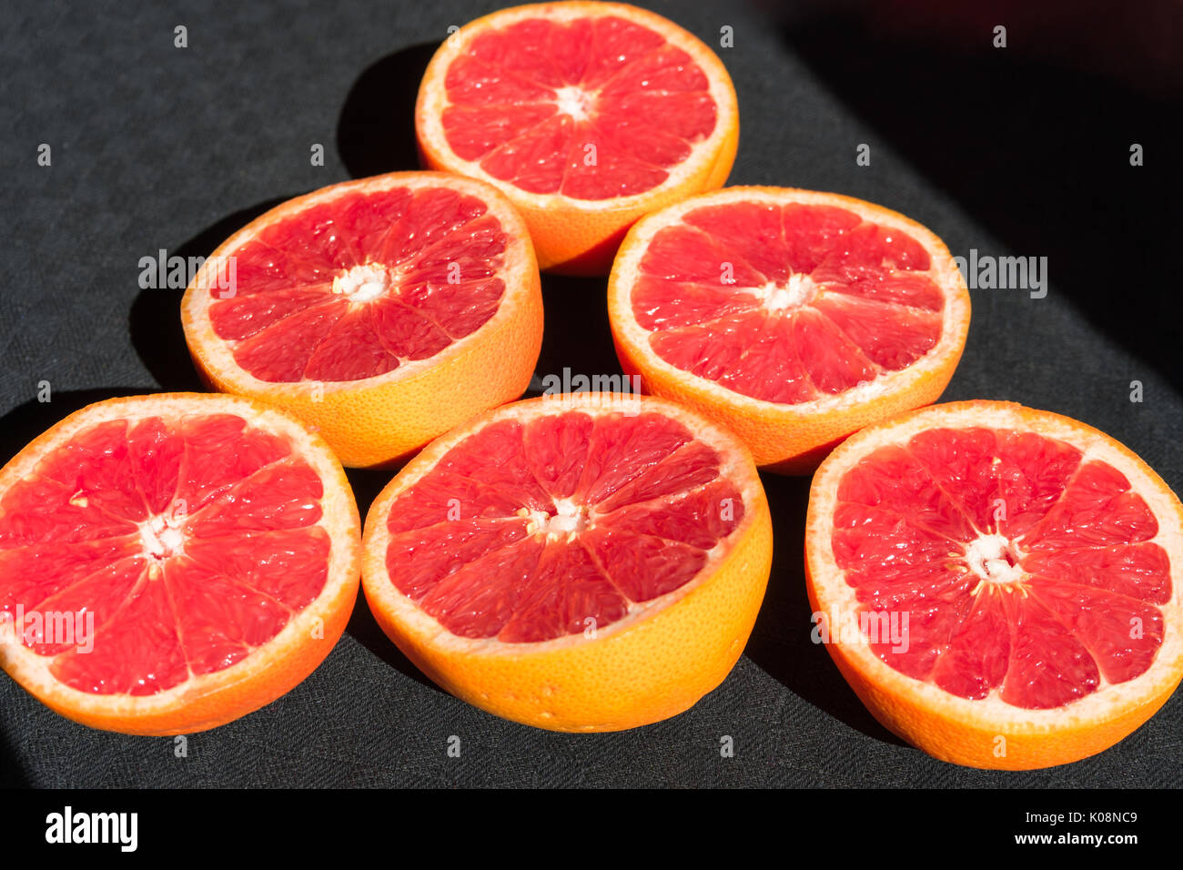 6 rosa Grapefruits auf schwarzem Hintergrund Stockfoto
