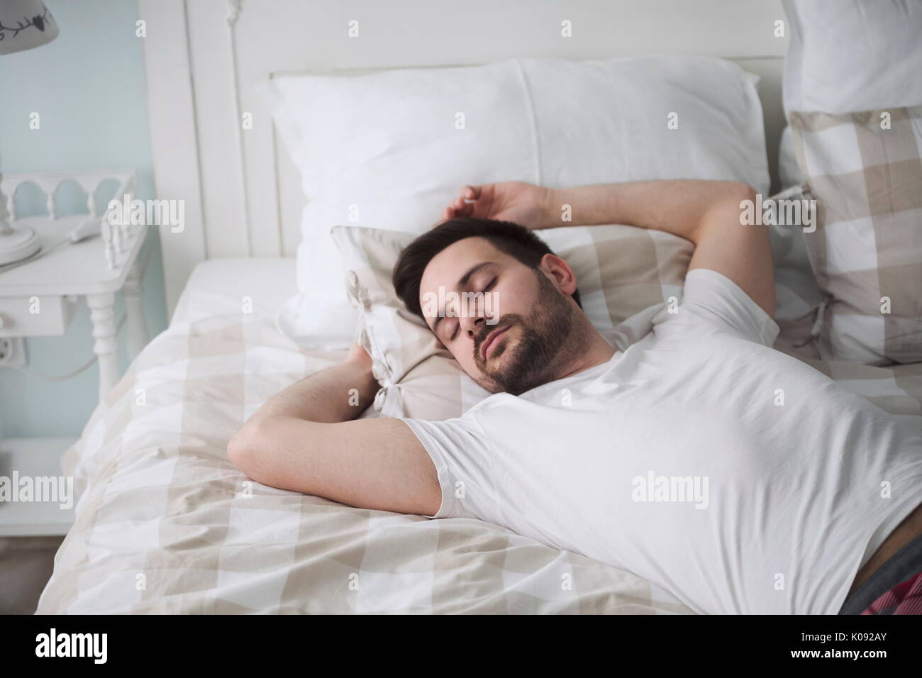 Schöner Mann schlafen auf Kissen im Bett Stockfoto