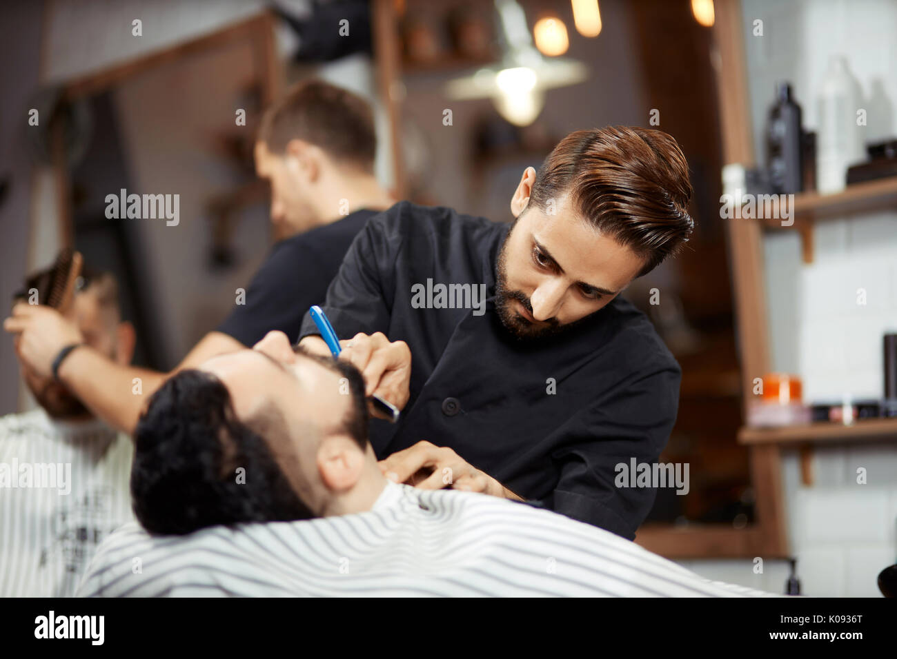 Konzentriert Friseur rasieren junge Mann Stockfoto