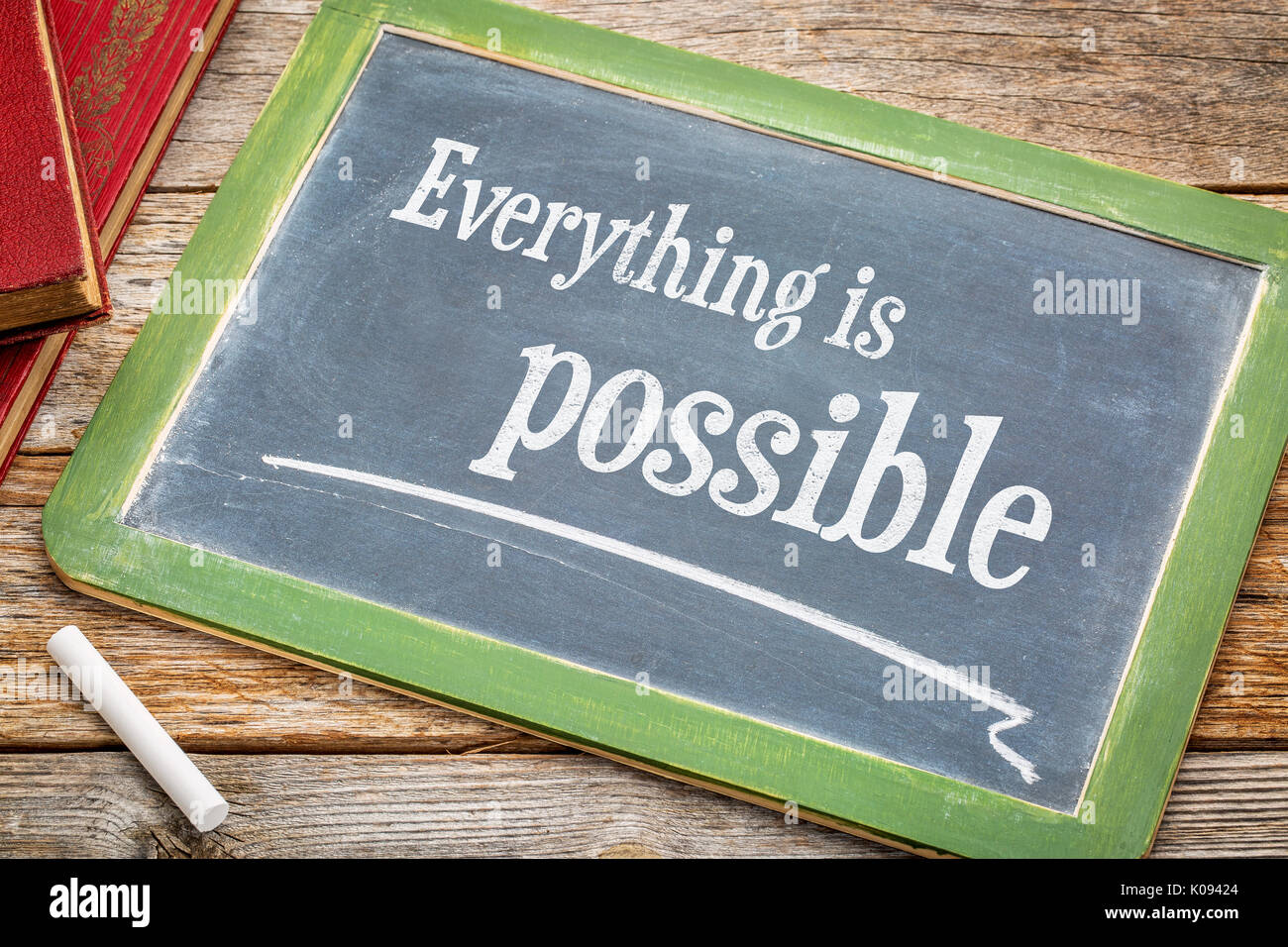 Alles ist möglich Anmelden - ein schiefer Tafel mit weißer Kreide und einen Stapel Bücher gegen rustikalen Holztisch Stockfoto