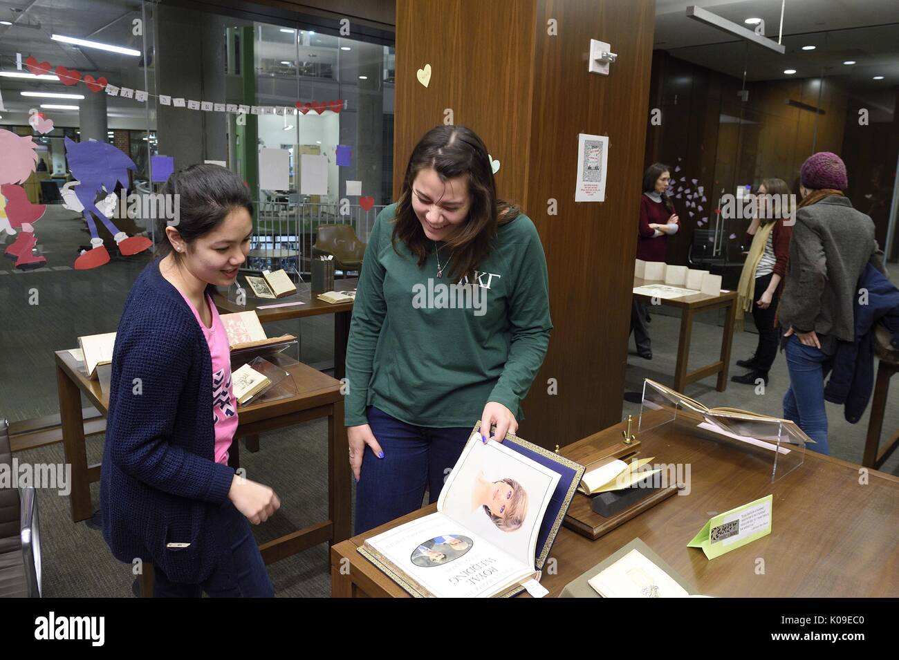Zwei weibliche Studenten in einer Seite Lachen in einem Buch auf die schmutzige Bücher und Sehnsucht sieht Veranstaltung in der Bibliothek, 11. Februar 2016. Stockfoto