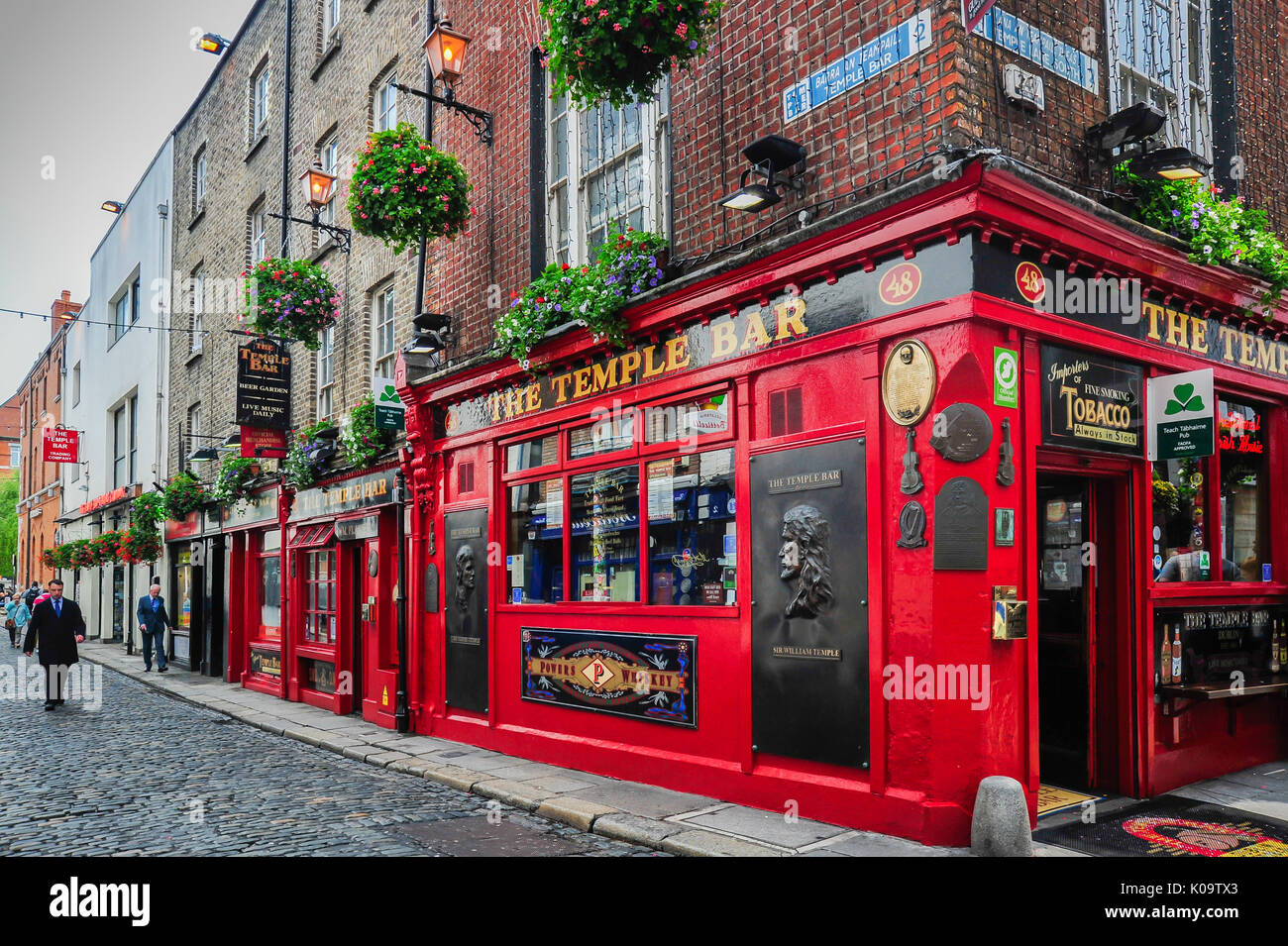 Ein Geschäftsmann geht eine Straße mit Kopfsteinpflaster in der Nähe der berühmten Temple Bar in Dublin, Irland Stockfoto