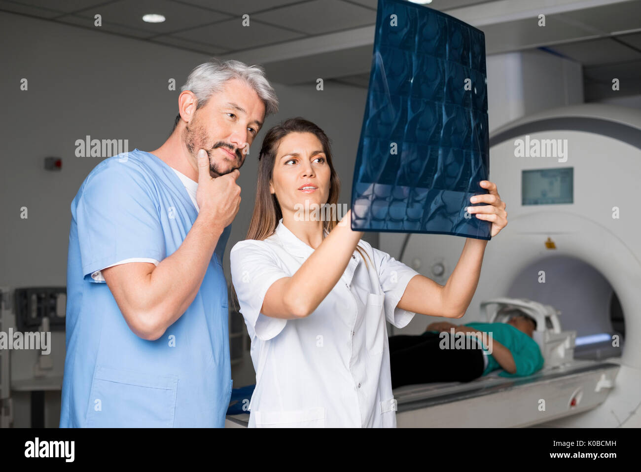 Ärzte Prüfung X-ray mit Patienten, der auf CT-Scan Maschine Stockfoto