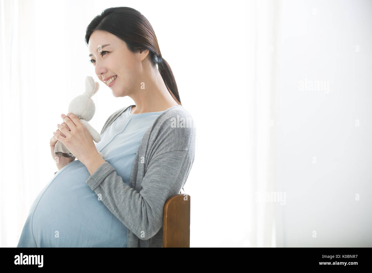 Seitenansicht der lächelnden schwangere Frau mit einer Puppe Stockfoto