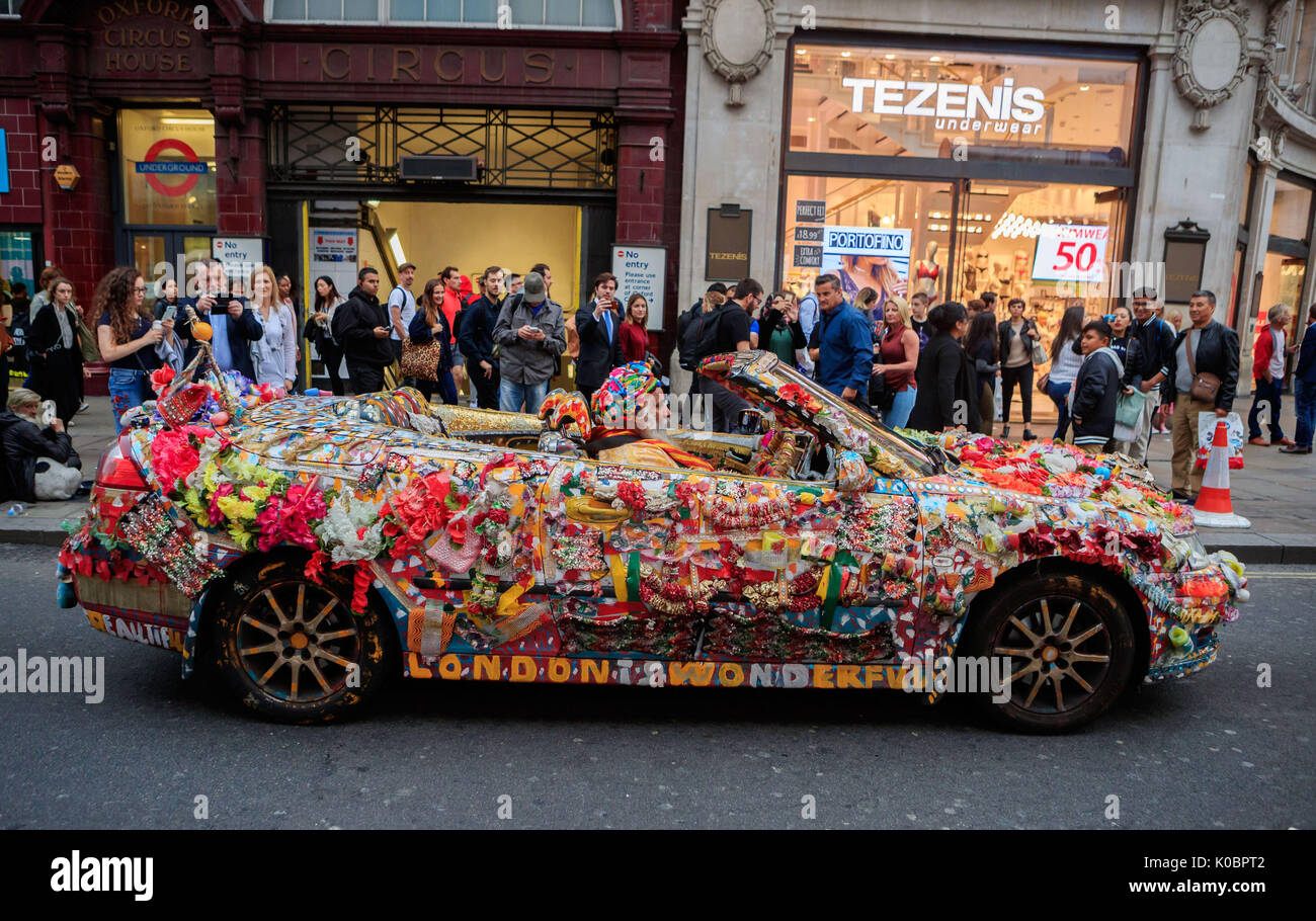 Ein Mann fährt eine aufwendig personalisierten und dekoriert Saab Auto in Oxford Circus, London. Stockfoto