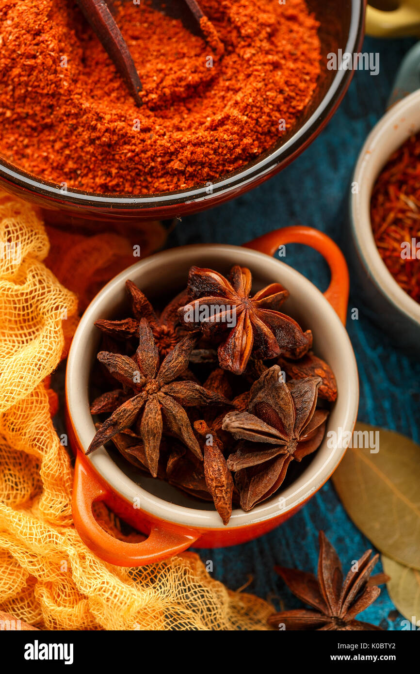 Trockene bunte Gewürze und Würzen Anis, Paprika, Safran, Pfeffer, Salz, Lorbeerblatt, Zimt in kleinen Schüsseln auf blauem Hintergrund Stockfoto