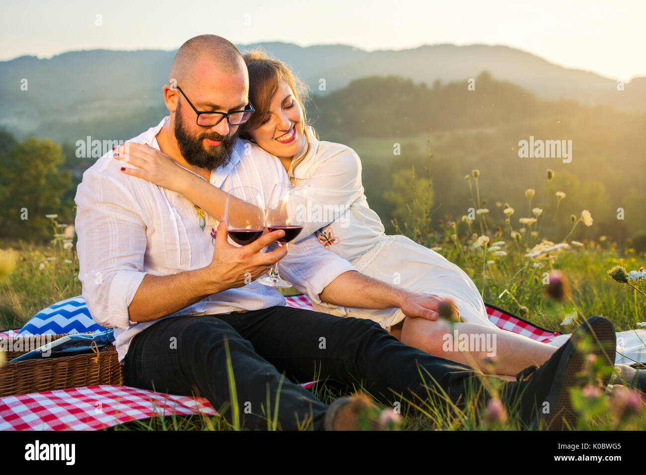 Paar sitzt auf einer Picknickdecke mit Weingläsern außerhalb Stockfoto