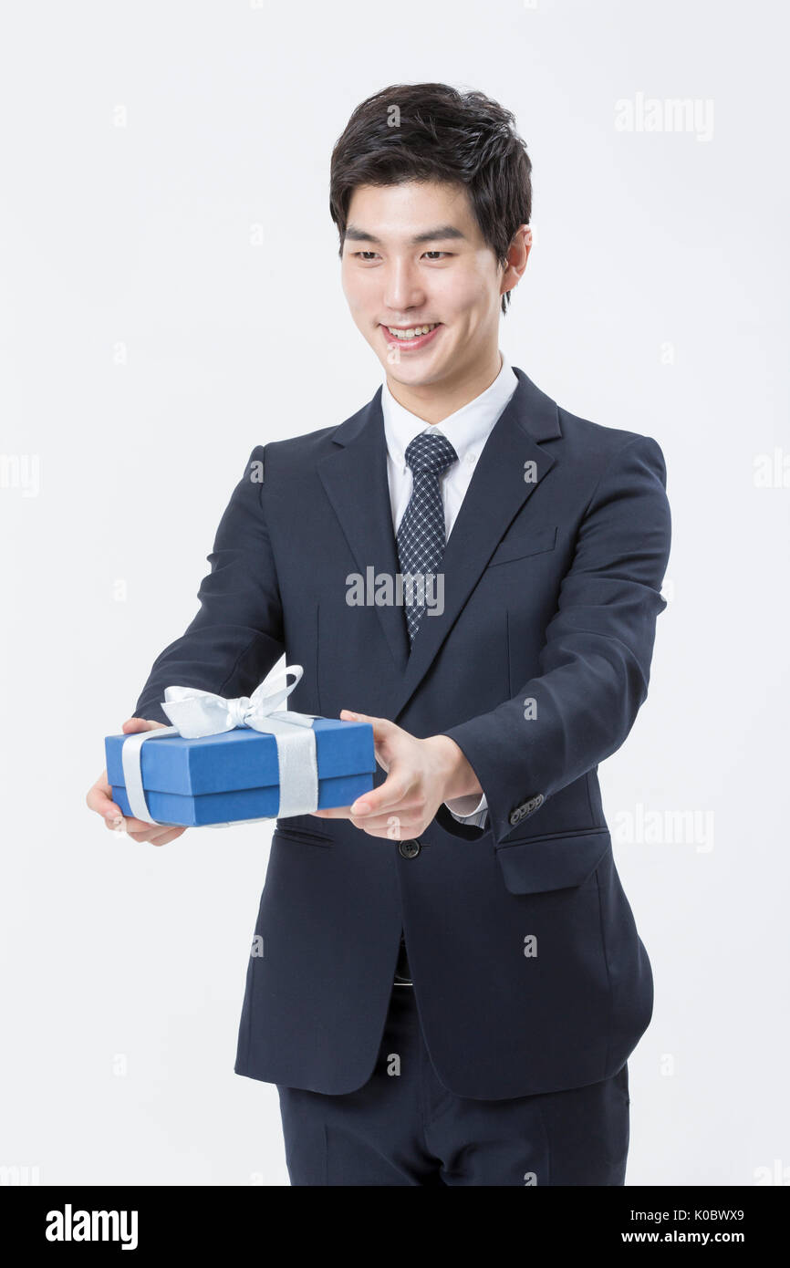 Junge lächelnde Geschäftsmann Holding ein Geschenk Box Stockfoto