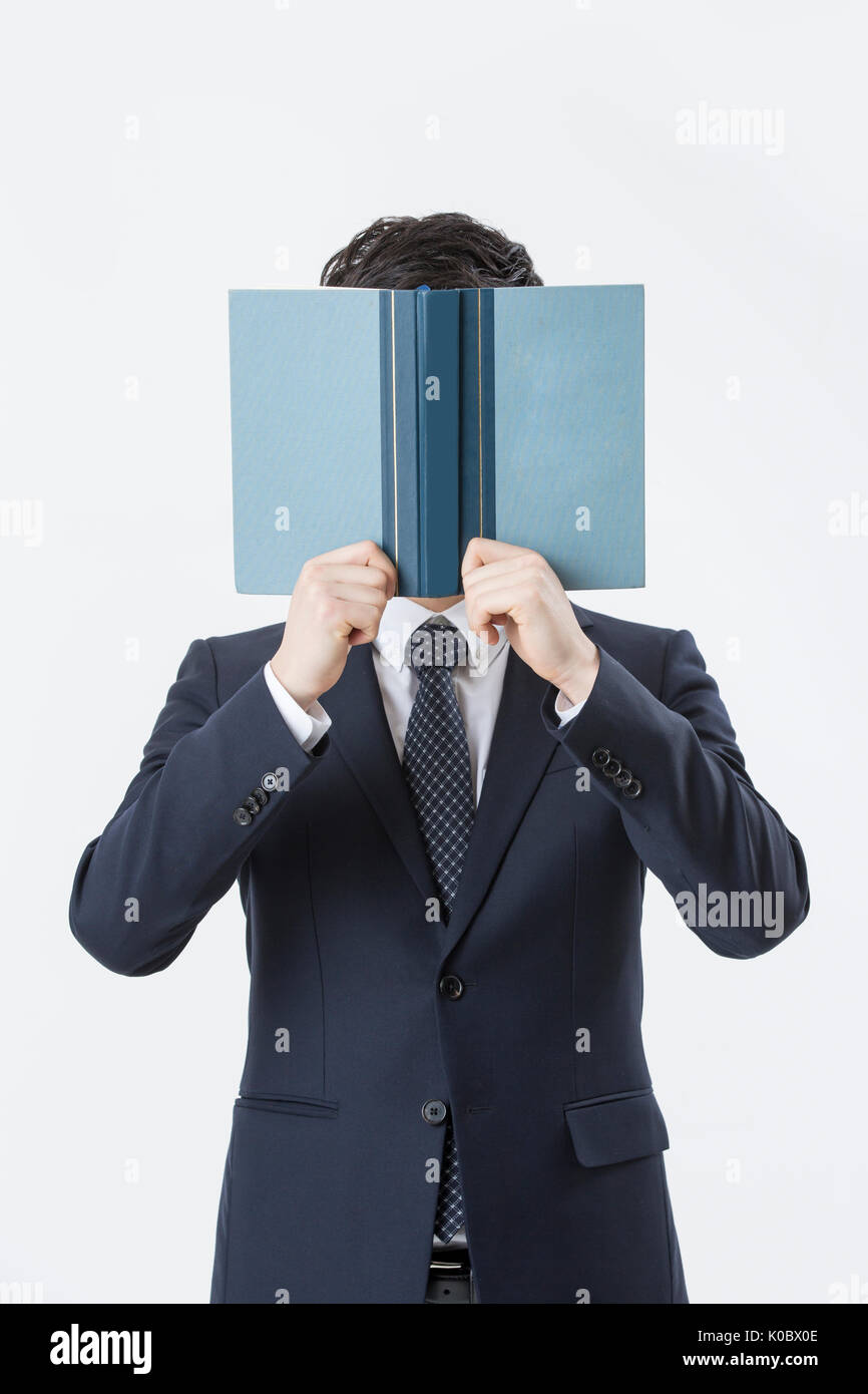 Büste erschossen der junge Geschäftsmann bedeckte sein Gesicht mit einem offenen Buch Stockfoto