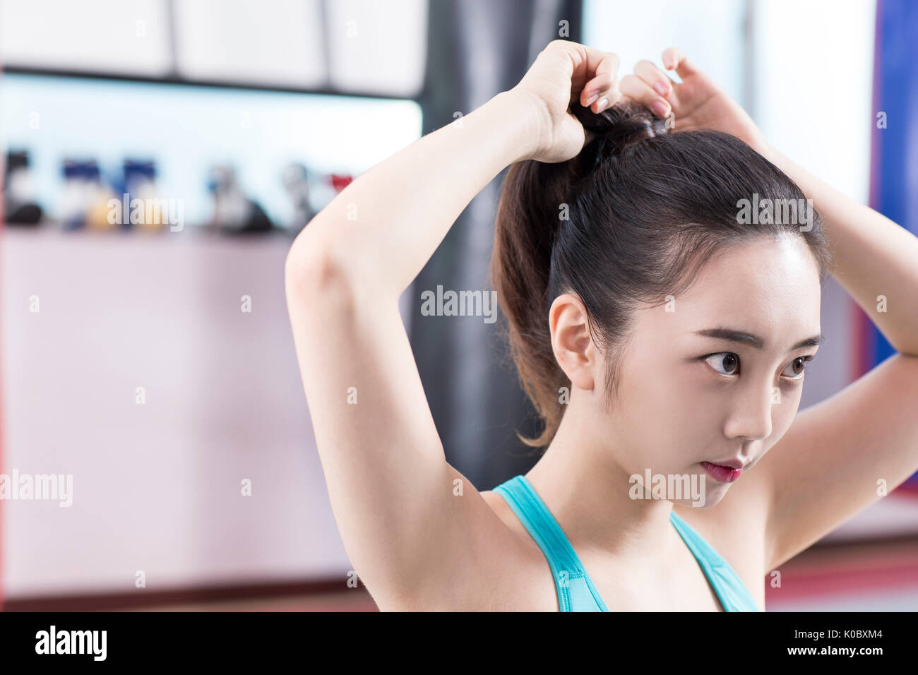 Porträt der jungen Frau in Sportkleidung band ihre Haare wieder im Fitnessstudio Stockfoto