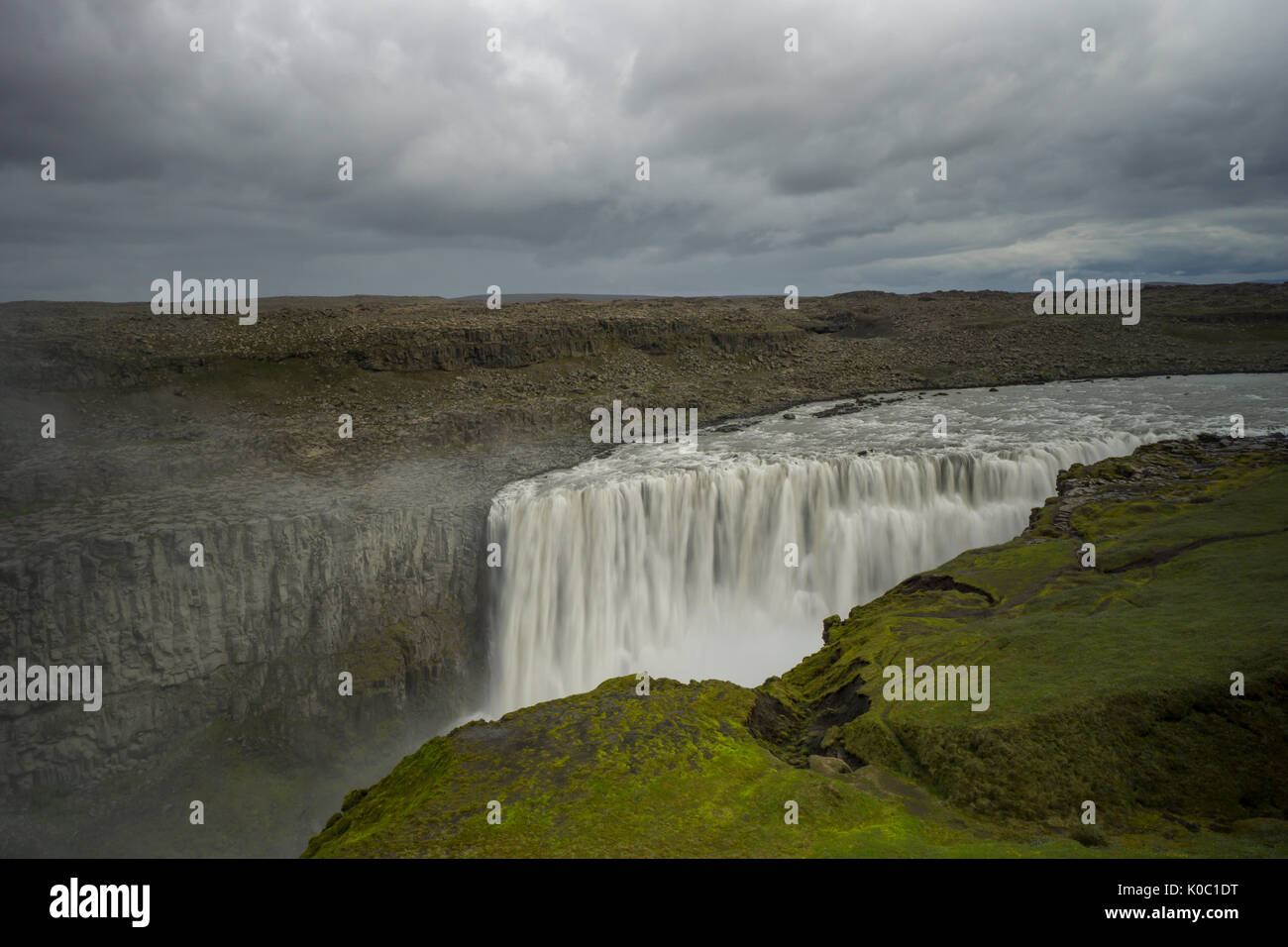 Island - Luftaufnahme des herrlichen detifoss Wasserfall hinter grünen Moos bedeckte Fläche Stockfoto