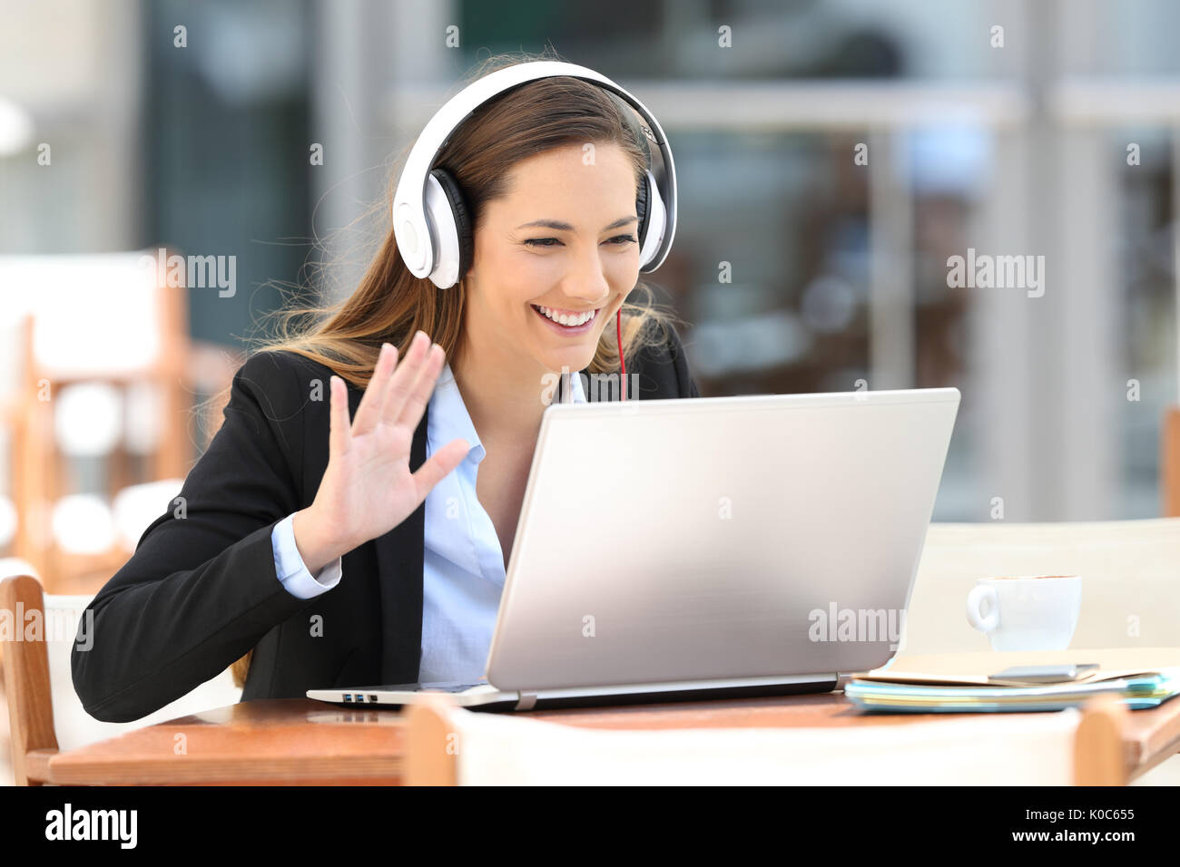 Executive in einer Videokonferenz mit einem Laptop und Kopfhörer in einem Coffee Shop Stockfoto
