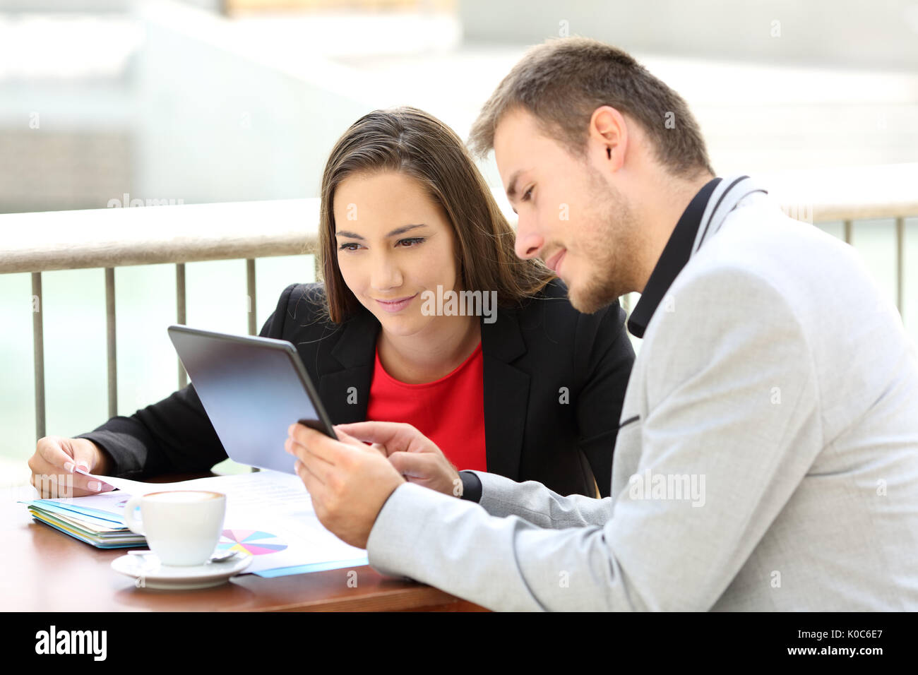 Zwei Führungskräfte Beratung auf der Linie mit einer Tablette in einem Café sitzen Stockfoto