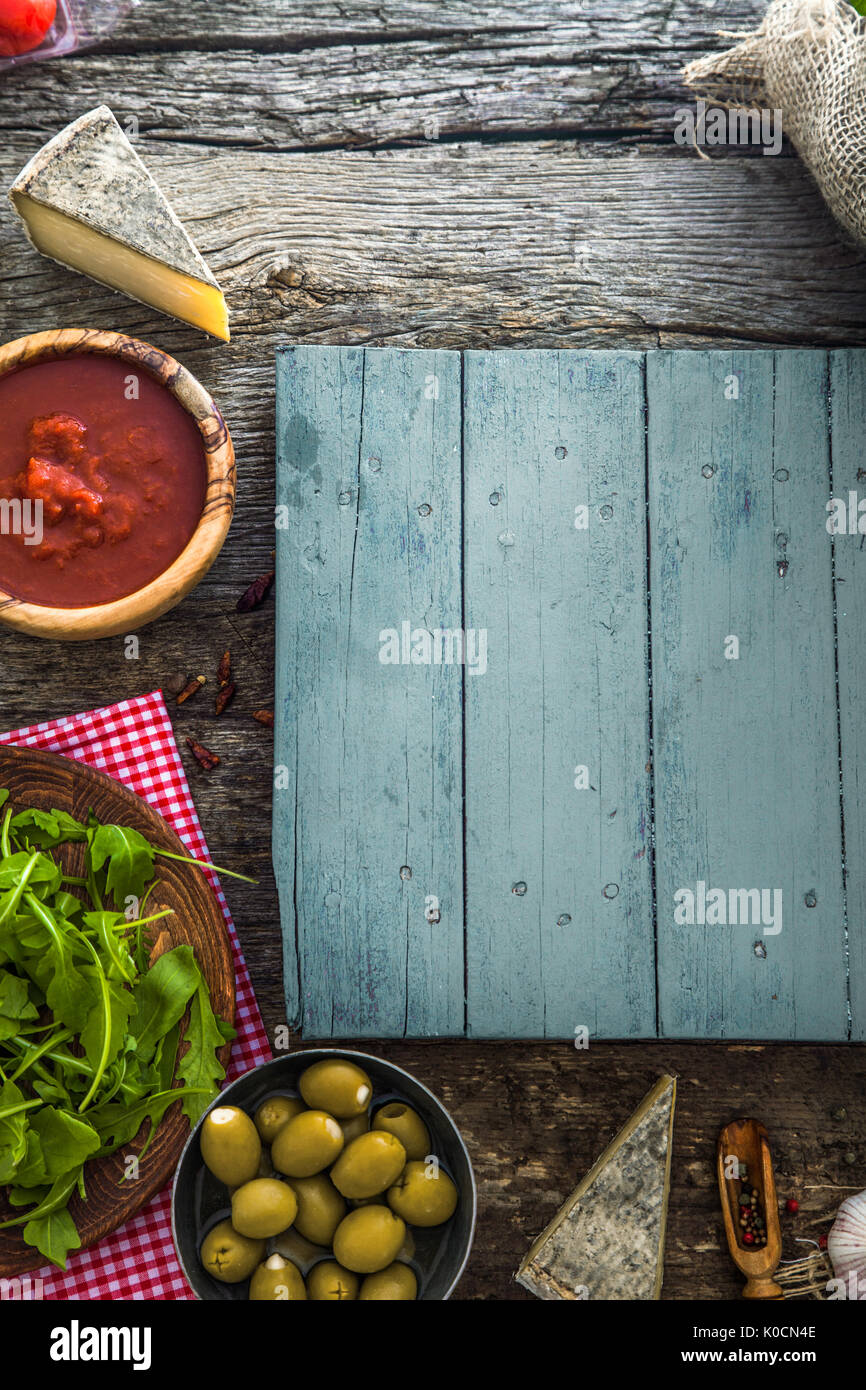 Holzbohlen mit Essen. Oliven, Basilikum, Tomaten und Zutaten auf Holz Stockfoto