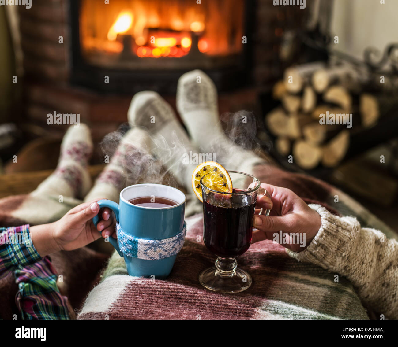 Wärmend und entspannend in der Nähe von Kamin. Frau Füße in der Nähe von der Tasse heißes Getränk am Kamin. Stockfoto