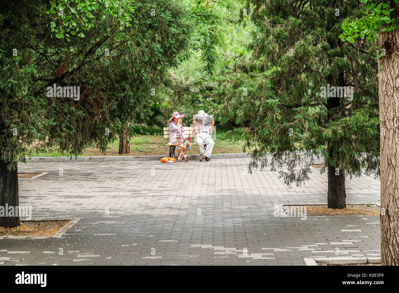 Ein pensionierter Chinesische paar Lesen von Zeitungen in einer ruhigen Ecke des Parks Stockfoto