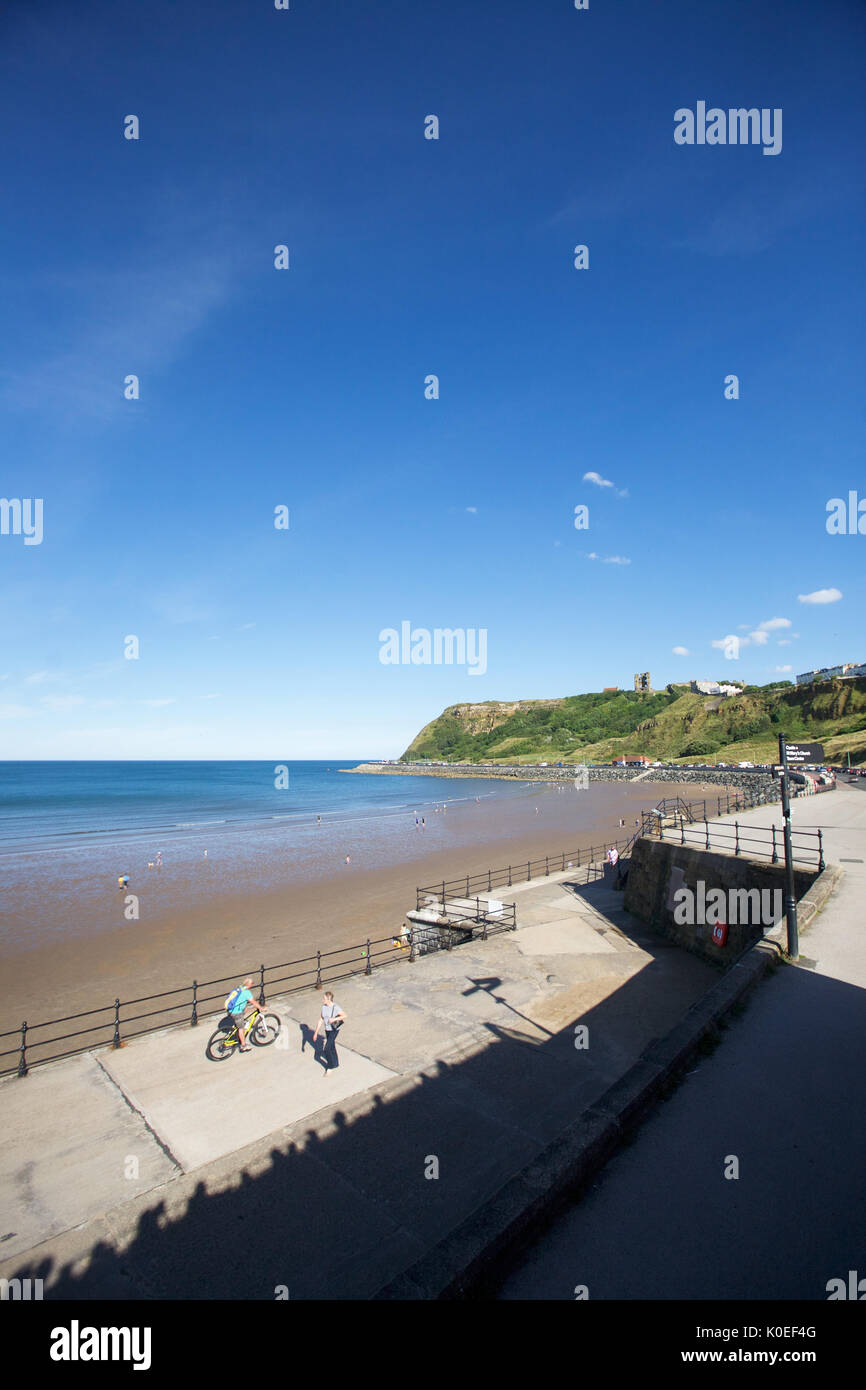 Blick auf Scarborough Castle von North Bay Scarborough mit Radfahrer und Spaziergänger auf der Promenade Stockfoto