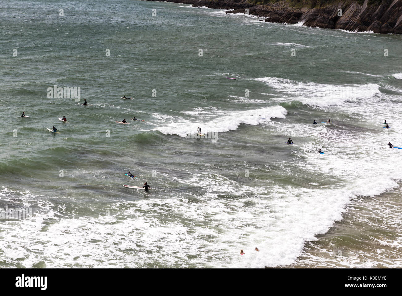 Eine Szene mit Sufers saßen auf ihren Surfbrettern wartet eine Welle an Caswell Bay auf der Halbinsel Gower in Wales, UK zu fangen Stockfoto