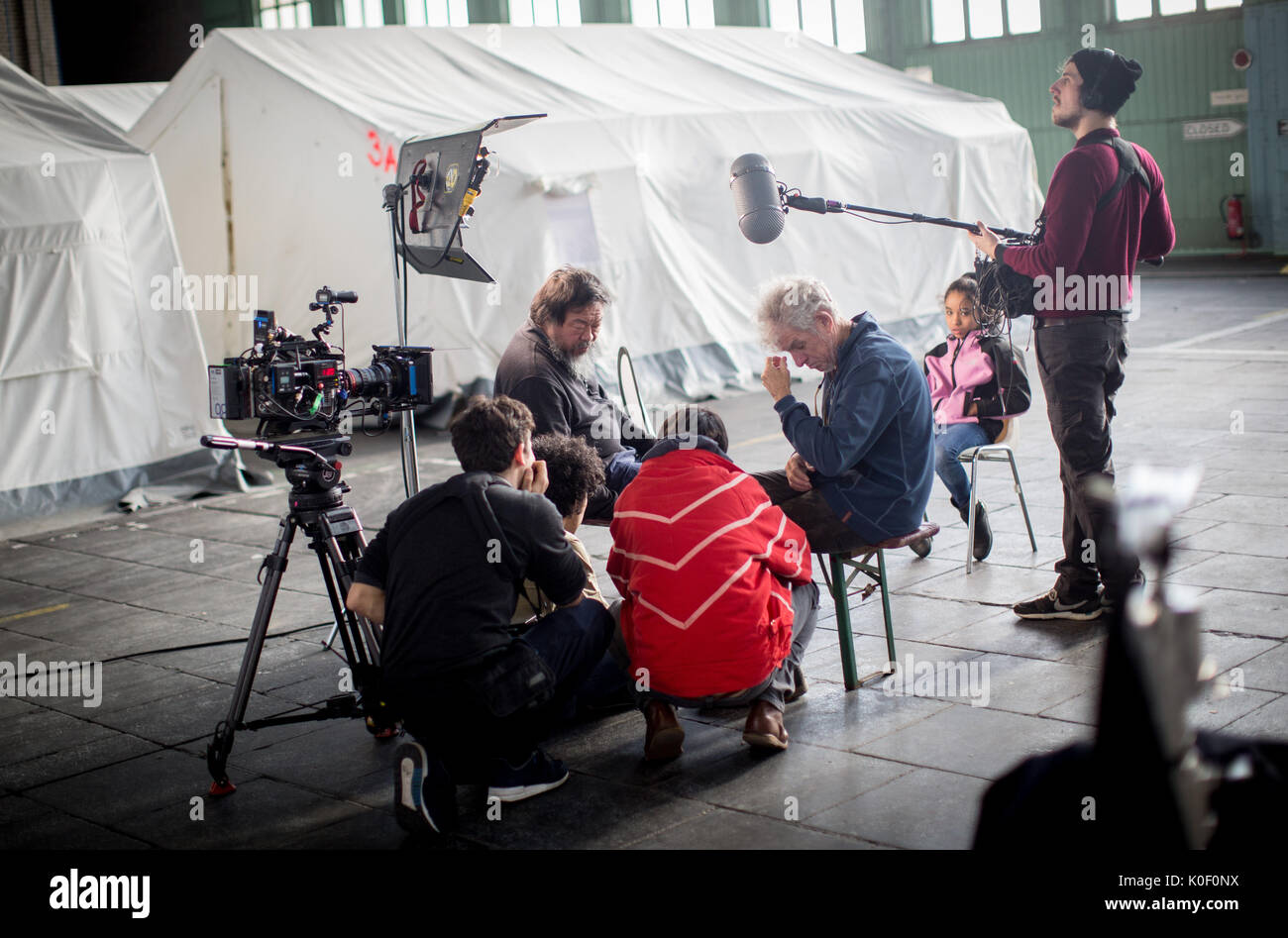 Archiv - Der chinesische Künstler Ai Weiwei mit seinem Filmteam in einem Hangar des Flüchtlings Notunterkünfte im ehemaligen Flughafen Tempelhof in Berlin, Deutschland, 10. Februar 2016 spricht. Im Reich der Mitte verfolgt, gefeiert wie ein Superstar in den Westen: Die chinesischen Exil Künstler und politischer Aktivist Ai Weiwei wird 60 Jahre alt. Foto: Kay Nietfeld/dpa Stockfoto