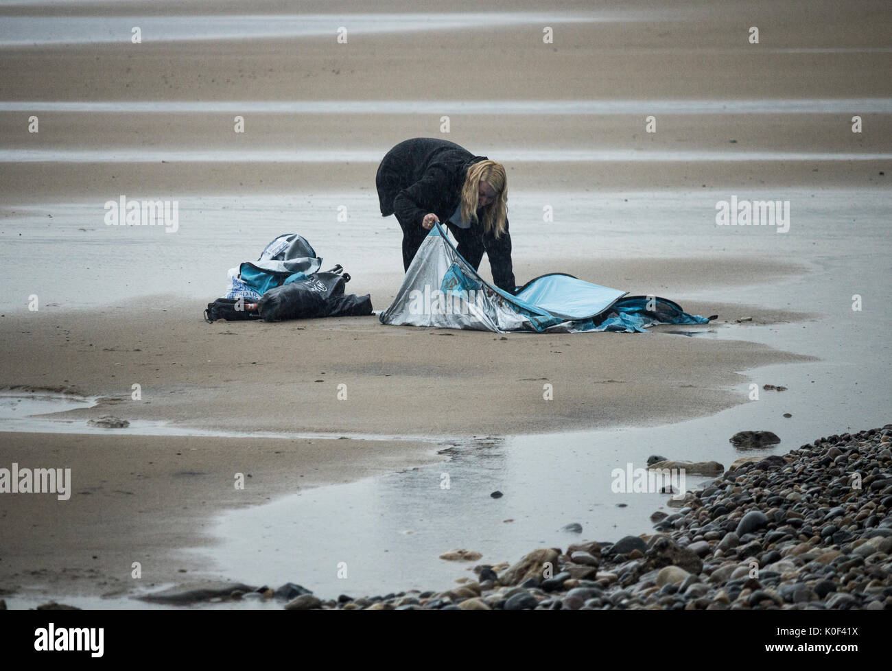 Saltburn am Meer, North Yorkshire, England, UK. 23 Aug, 2017. UK. Wetter: Während der Süden Osten der wärmste Tag im August so weit am Mittwoch sehen kann, ist es Donner und strömendem Regen an Saltburn auf der North Yorkshire Küste als Band der Regen langsam löscht die nördliche Hälfte der UK. Im Bild: Eine Frau, die das Verstecken von den sintflutartigen Regen und Donner in Tierheim/Zelt auf Saltburn Strand entscheidet, einen Lauf für Sie zu machen. Credit: ALAN DAWSON/Alamy leben Nachrichten Stockfoto