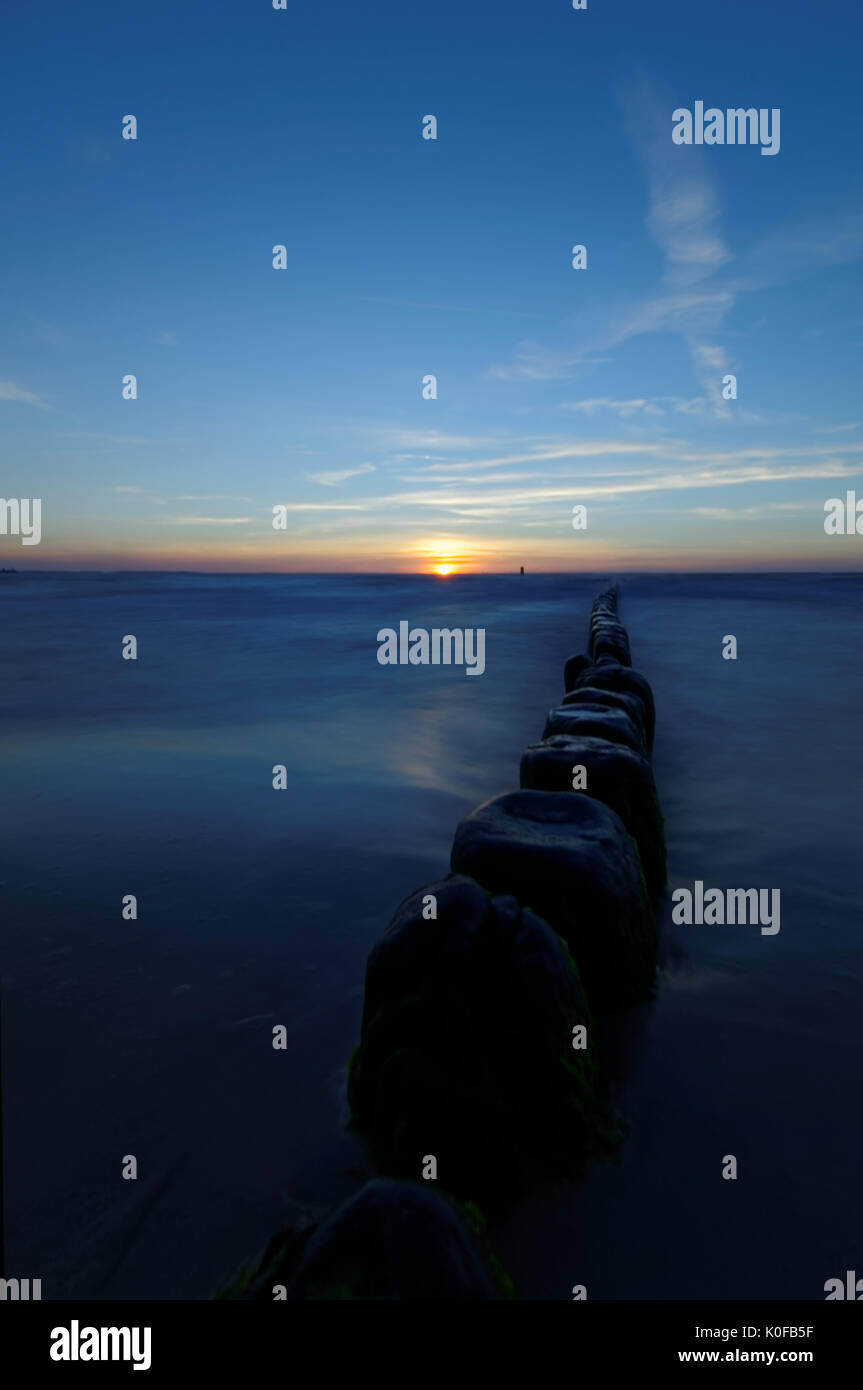 Sonnenuntergang über dem Meer. Wellenbrecher auf der glatten Oberfläche des Meeres. Stockfoto